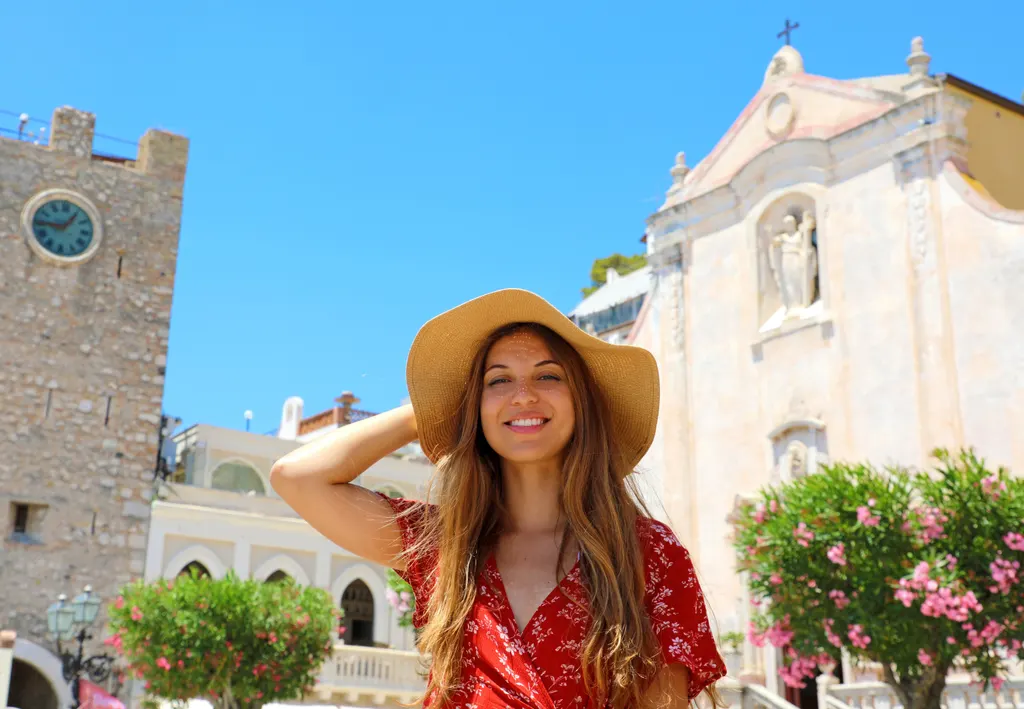Una donna sorridente con un cappello di paglia in un borgo siciliano